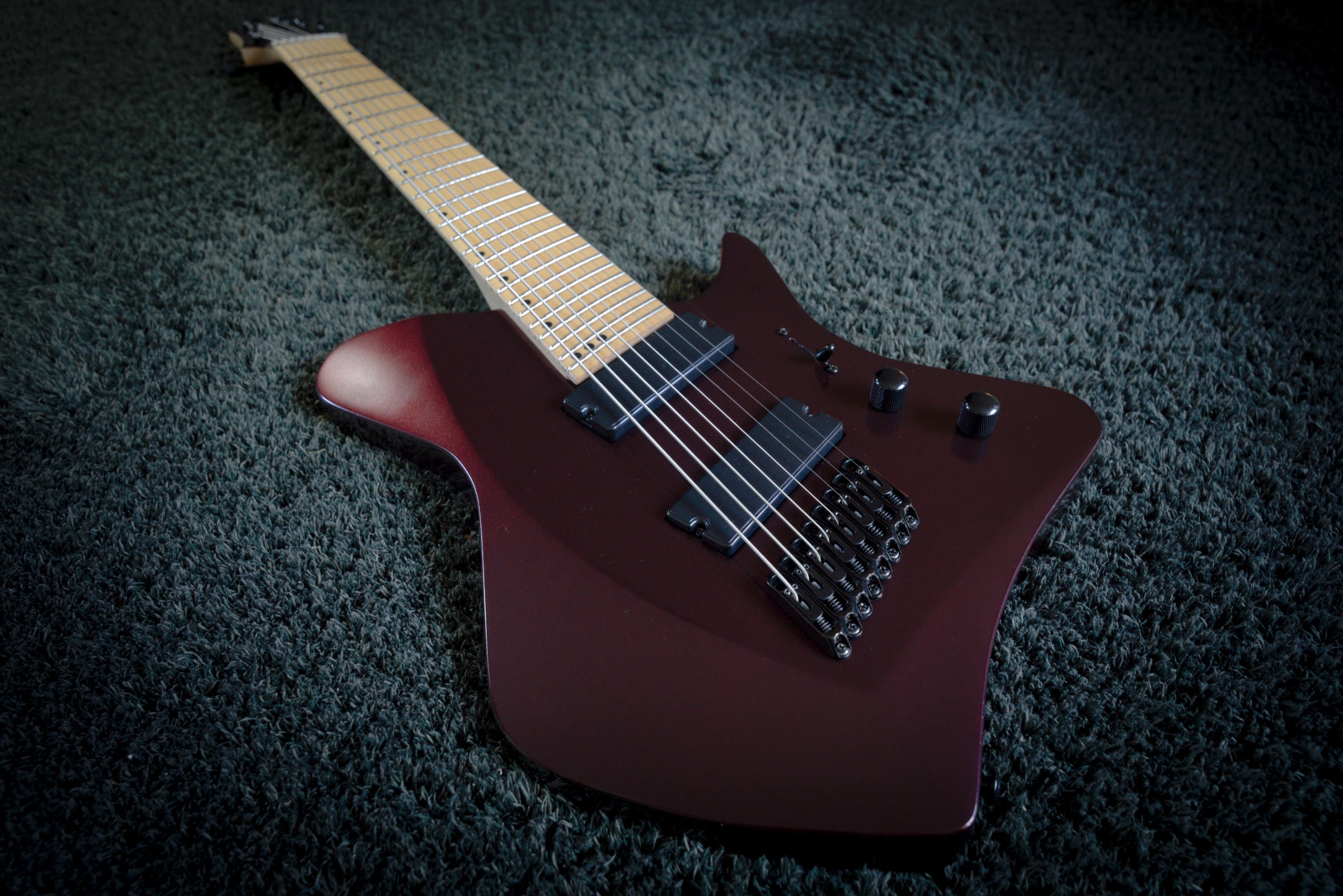 Custom 3D-printed body guitar in a deep red finish, resting on a dark carpet.